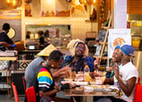 Un grupo de comensales disfruta la comida de África occidental y el ambiente informal del restaurante ChopnBlock.