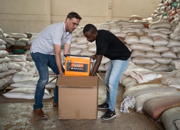Felix Brooks-church, cofundador de Sanku, y Dawit Biruk Zegeye, gerente de desarrollo de negocios de Sanku, desempacan un dosificador en la fábrica Addis Flour Mill en Burayu, Etiopía. El dosificador entrega dosis precisas de micronutrientes esenciales para la harina durante el proceso de molienda. Foto: © Rolex / Aurélie Marrier d’Unienville.