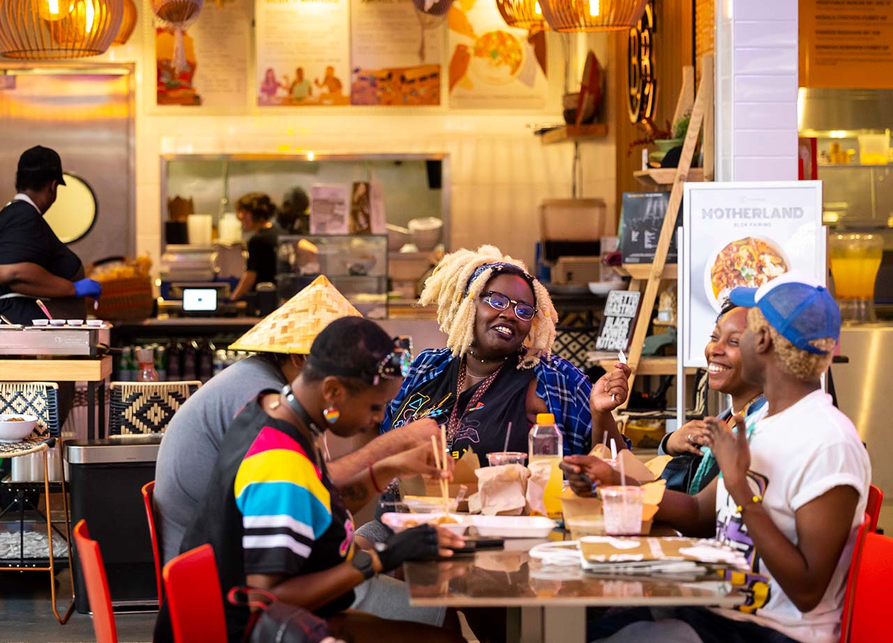 Un grupo de comensales disfruta la comida de África occidental y el ambiente informal del restaurante ChopnBlock.