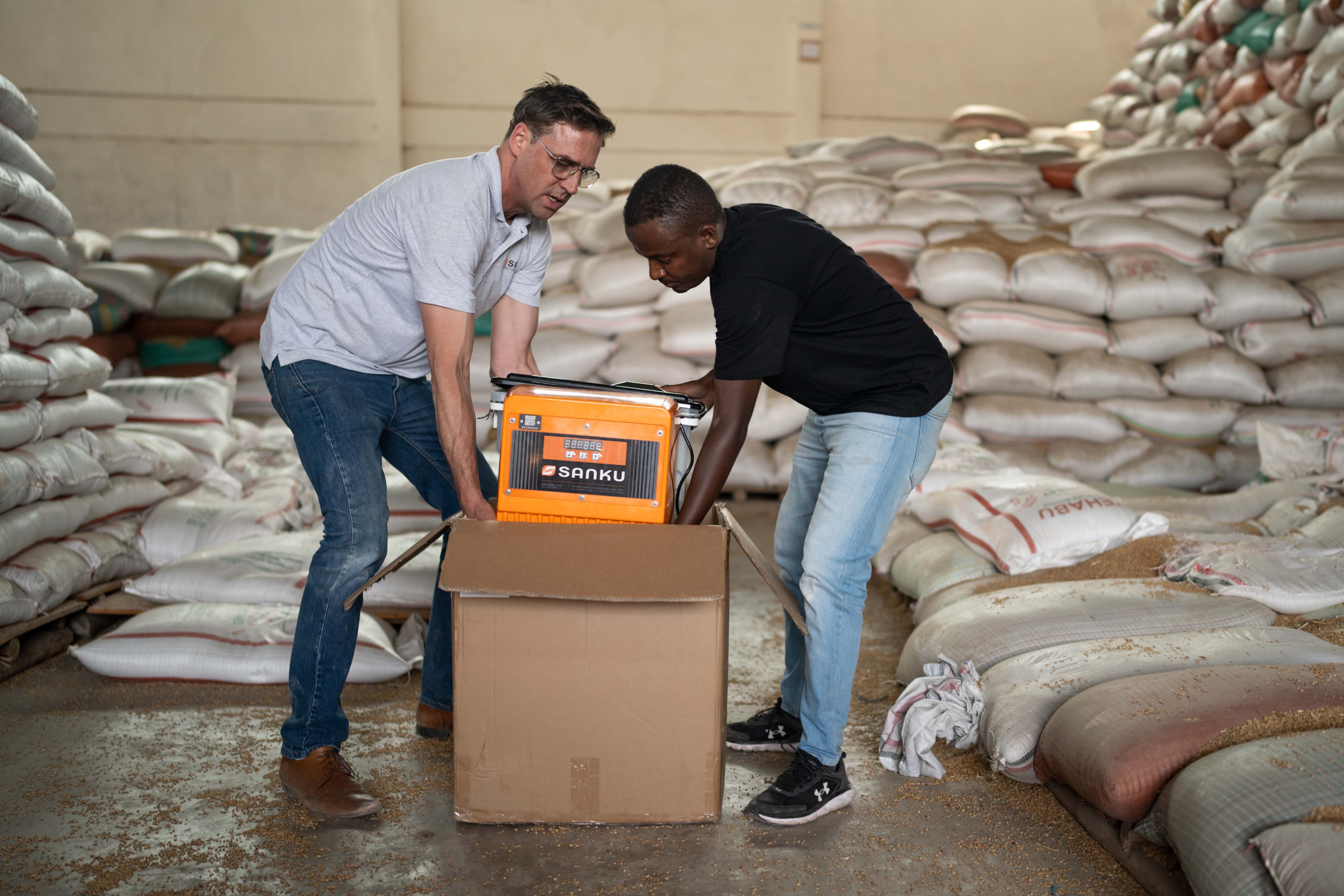 Felix Brooks-church, cofundador de Sanku, y Dawit Biruk Zegeye, gerente de desarrollo de negocios de Sanku, desempacan un dosificador en la fábrica Addis Flour Mill en Burayu, Etiopía. El dosificador entrega dosis precisas de micronutrientes esenciales para la harina durante el proceso de molienda. Foto: © Rolex / Aurélie Marrier d’Unienville.